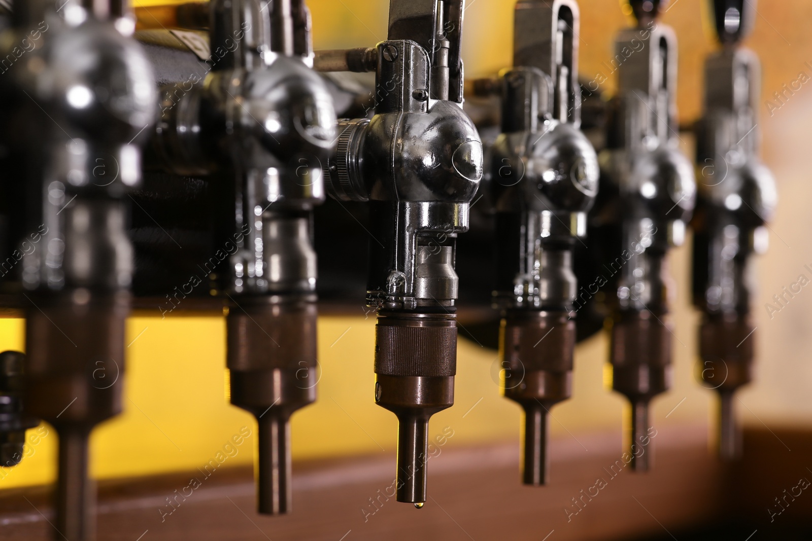 Photo of New modern beer taps in pub, closeup. Professional bar equipment