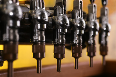 Photo of New modern beer taps in pub, closeup. Professional bar equipment