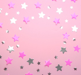 Photo of Frame made of confetti stars with space for text on pink background, top view. Christmas celebration