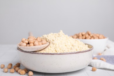Photo of Chickpea flour in bowl and seeds on white tiled table