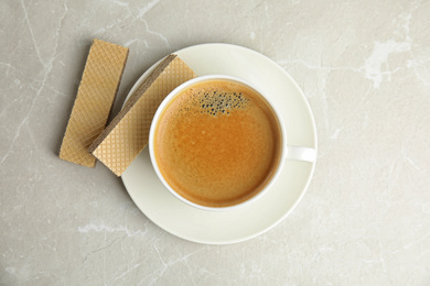 Photo of Delicious wafers and coffee for breakfast on grey marble table, flat lay