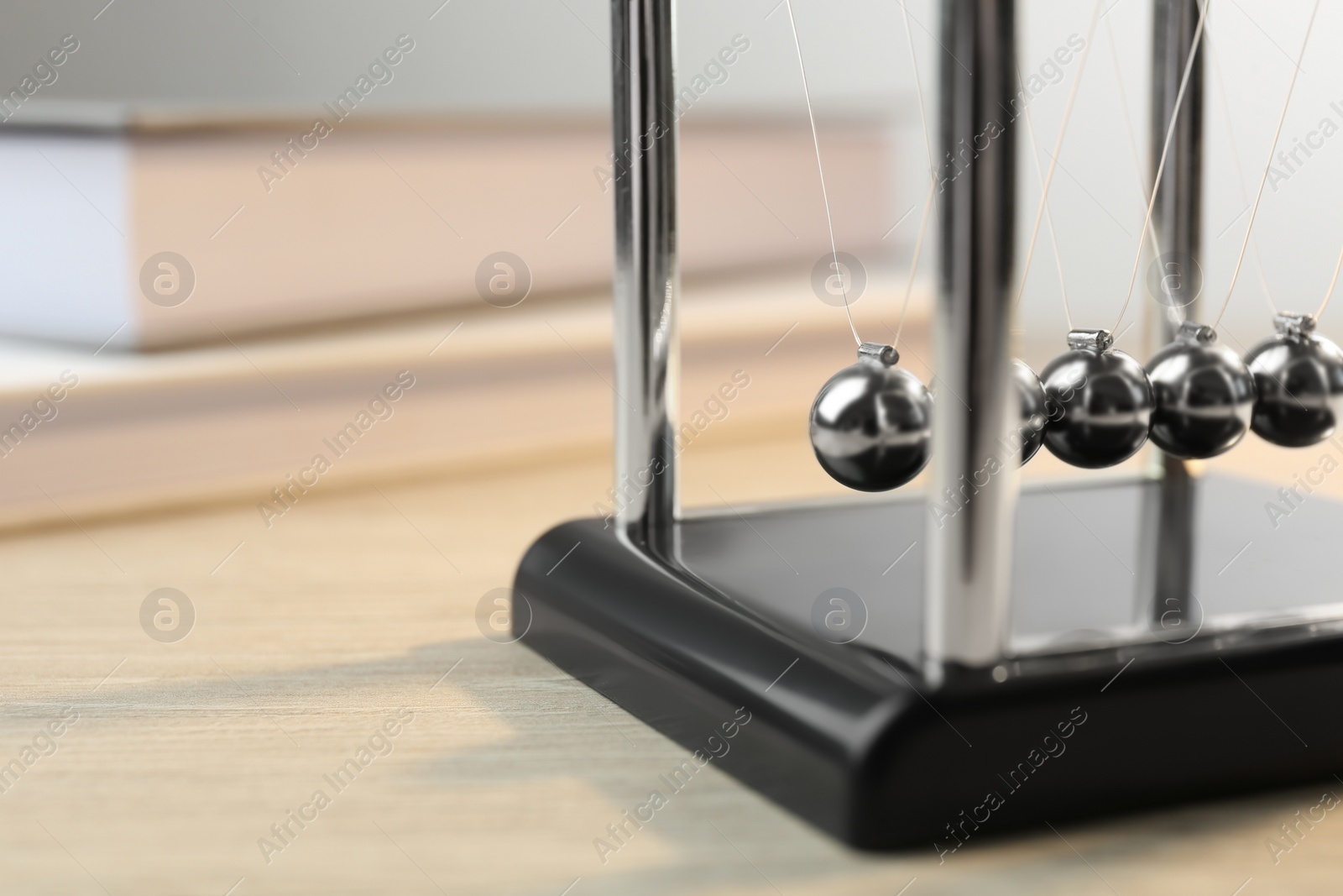 Photo of Newton's cradle on wooden table, closeup. Physics law of energy conservation