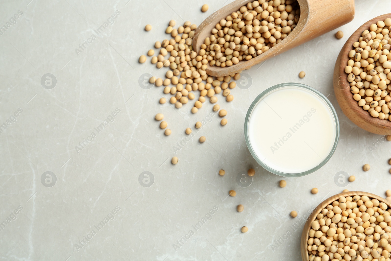 Photo of Fresh soy milk and beans on light grey table, flat lay. Space for text