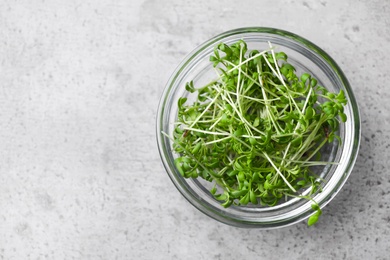 Photo of Fresh organic microgreen in bowl on grey table, top view. Space for text