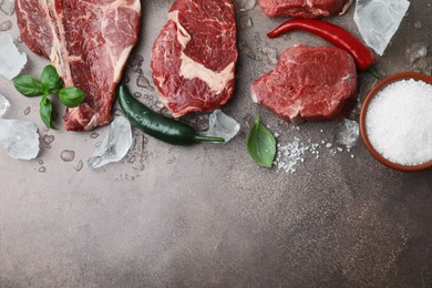 Photo of Flat lay composition with cut fresh beef meat on brown table. Space for text