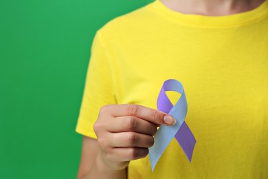 Image of World Arthritis Day. Woman with blue and purple awareness ribbon on green background, closeup