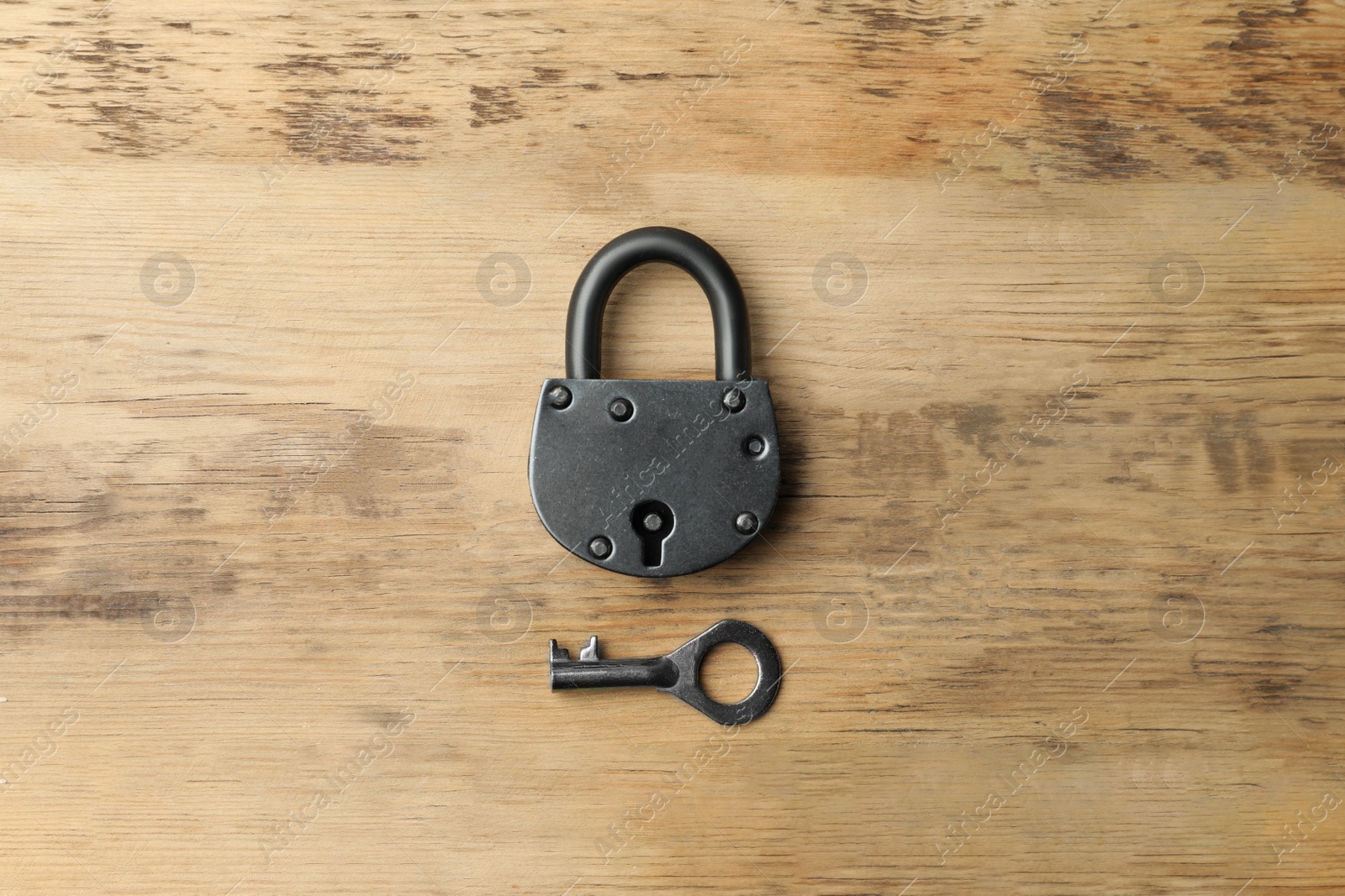 Photo of Steel padlock and key on wooden background, top view. Safety concept