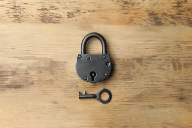 Photo of Steel padlock and key on wooden background, top view. Safety concept