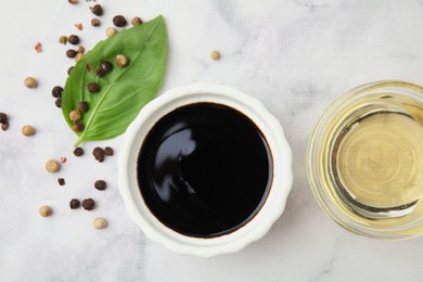 Bowl with balsamic vinegar and ingredients on white marble table, flat lay