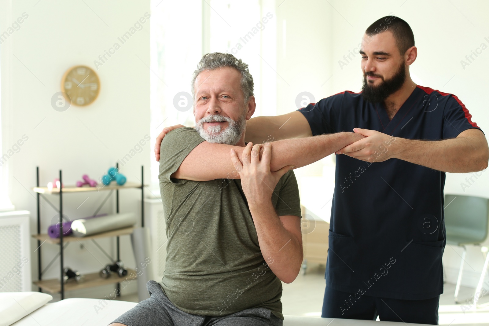 Photo of Physiotherapist working with patient in clinic. Rehabilitation therapy