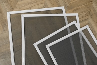 Photo of Set of window screens on wooden floor, flat lay