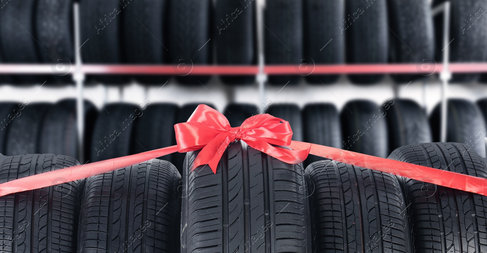 Image of Car tires tied with red ribbon in auto store. Banner design