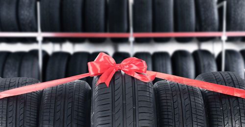 Car tires tied with red ribbon in auto store. Banner design