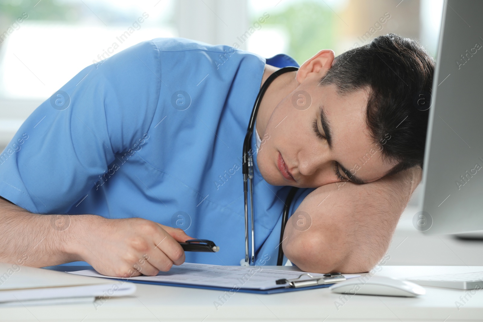 Photo of Exhausted doctor sleeping at workplace in hospital