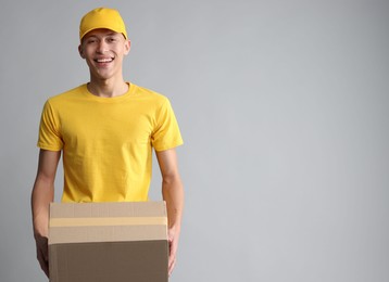 Photo of Happy courier with parcel on light grey background. Space for text