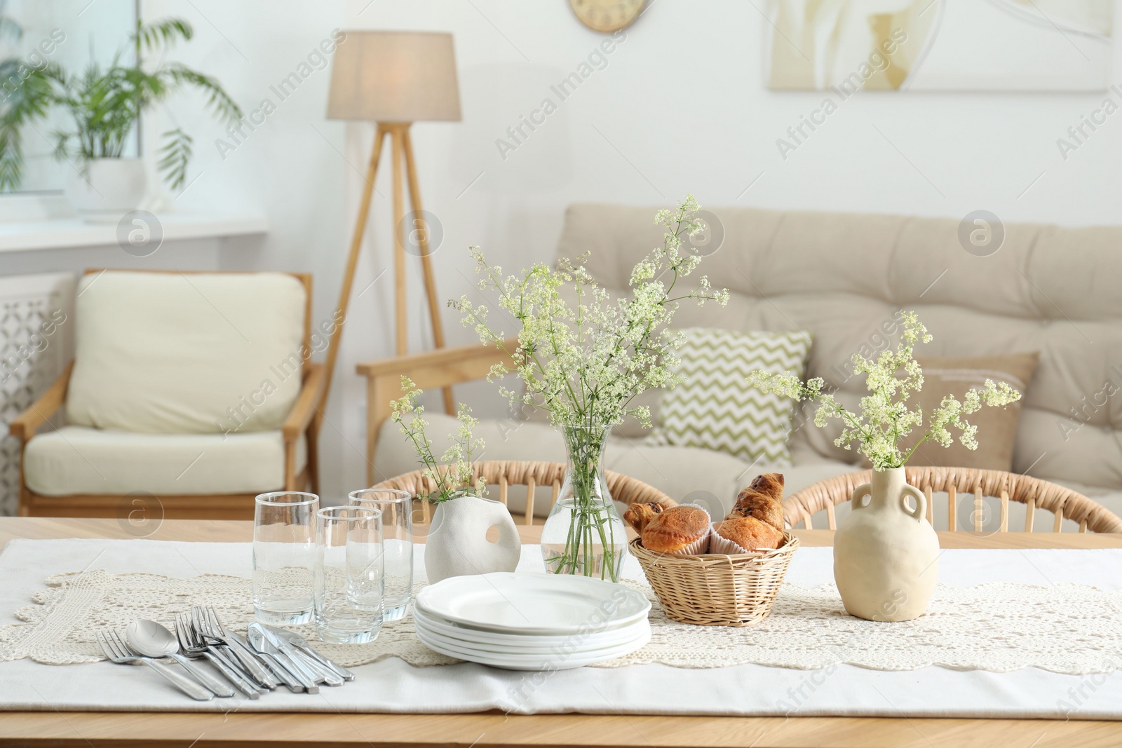 Photo of Clean dishes, flowers and fresh pastries on table in stylish dining room