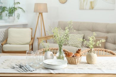Photo of Clean dishes, flowers and fresh pastries on table in stylish dining room