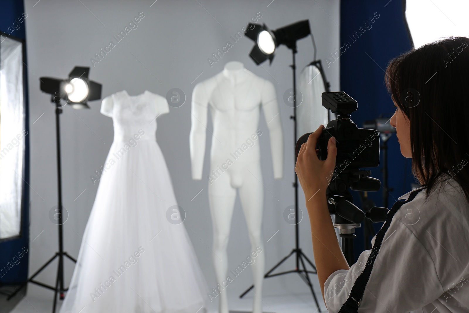 Photo of Professional photographer taking picture of ghost mannequins with stylish clothes in photo studio