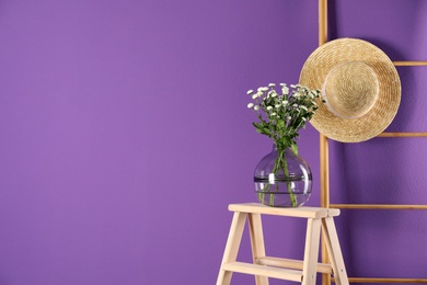 Stylish vase with chrysanthemum bouquet near purple wall. Space for text