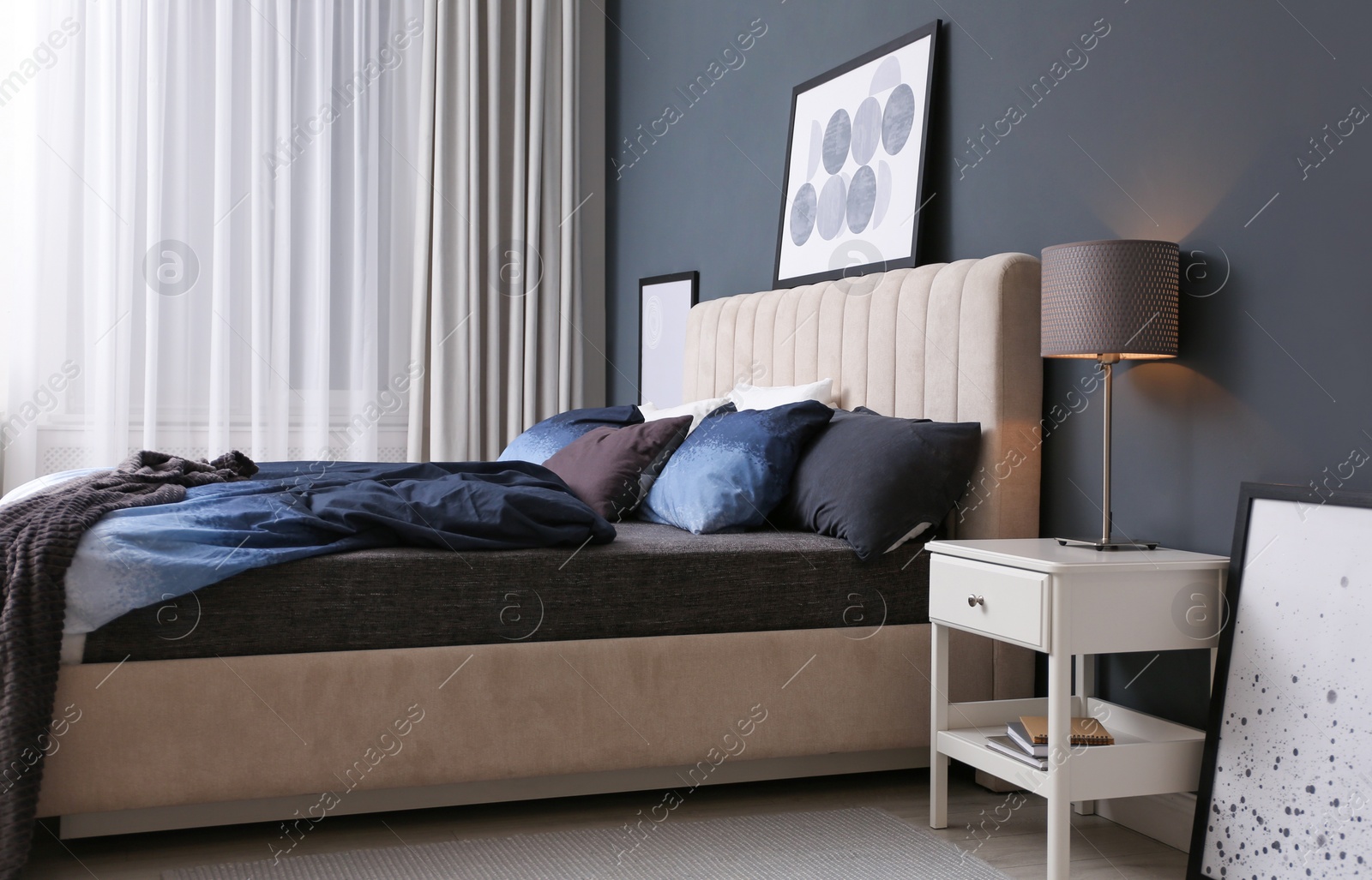 Photo of Comfortable bed with pillows and soft blanket in room. Stylish interior design