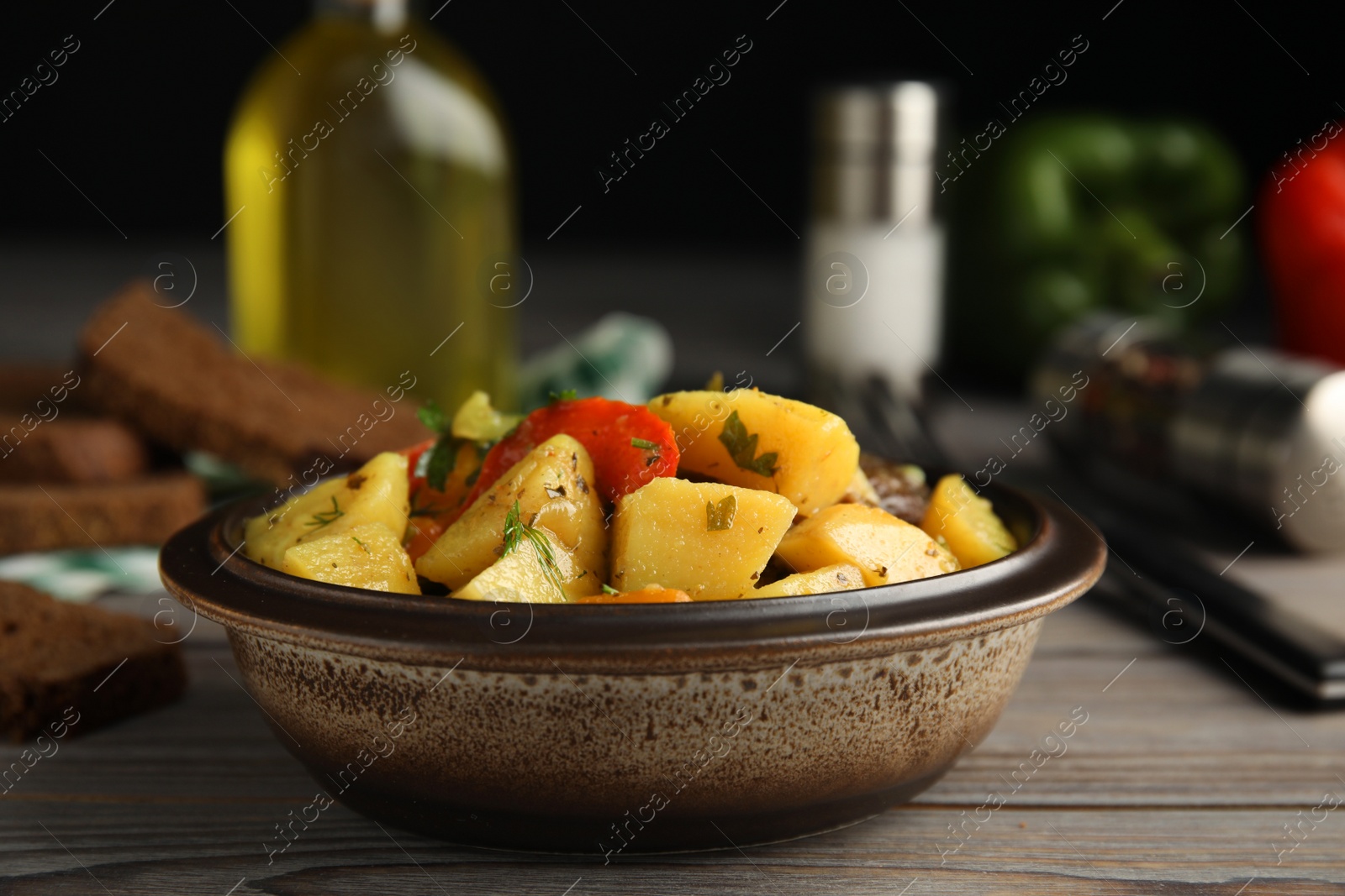 Photo of Tasty cooked dish with potatoes in earthenware served on wooden table