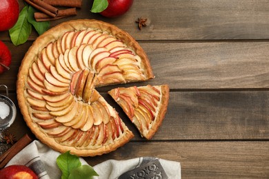 Photo of Delicious apple pie and ingredients on wooden table, flat lay. Space for text