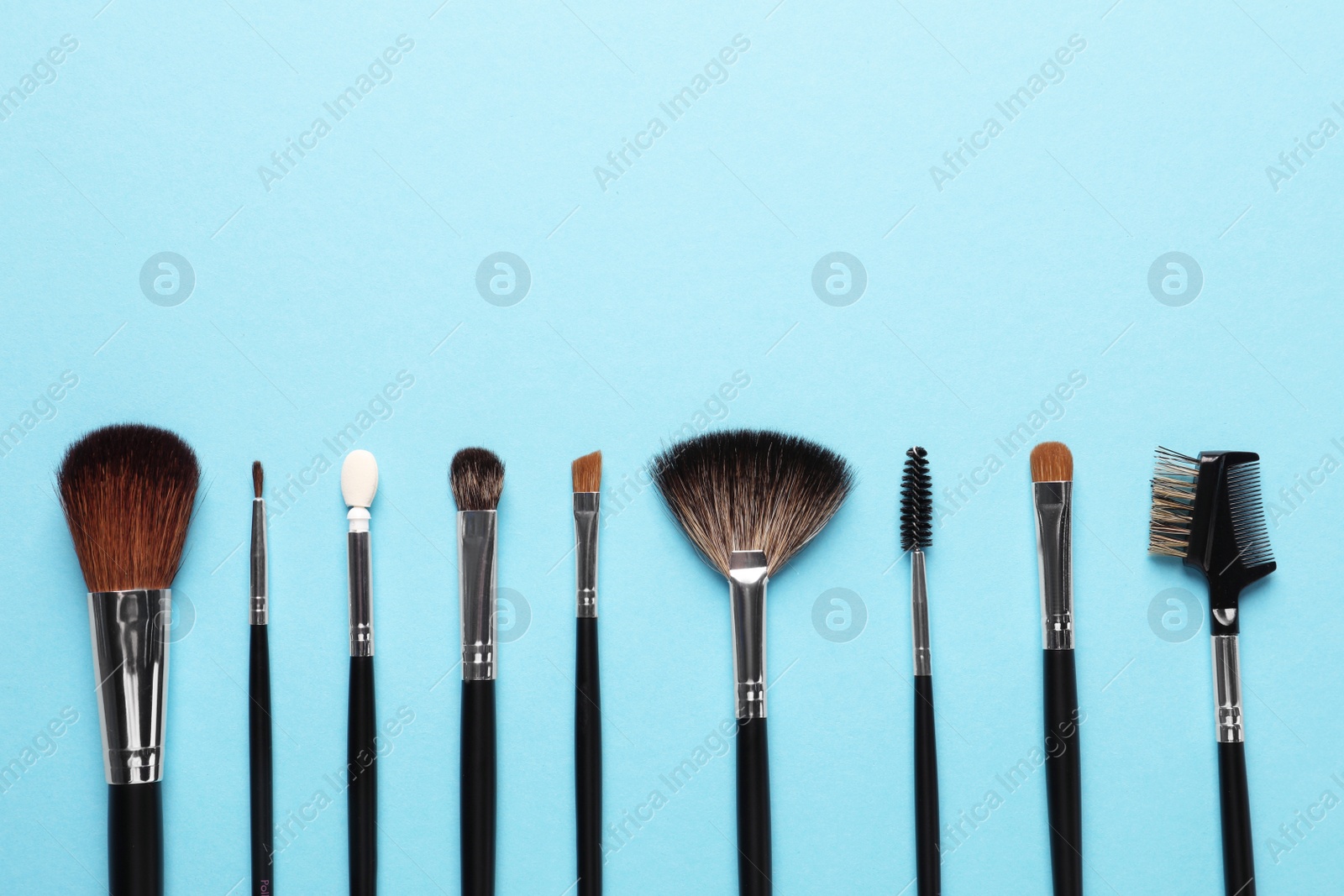 Photo of Set of makeup brushes on light blue background, flat lay. Space for text