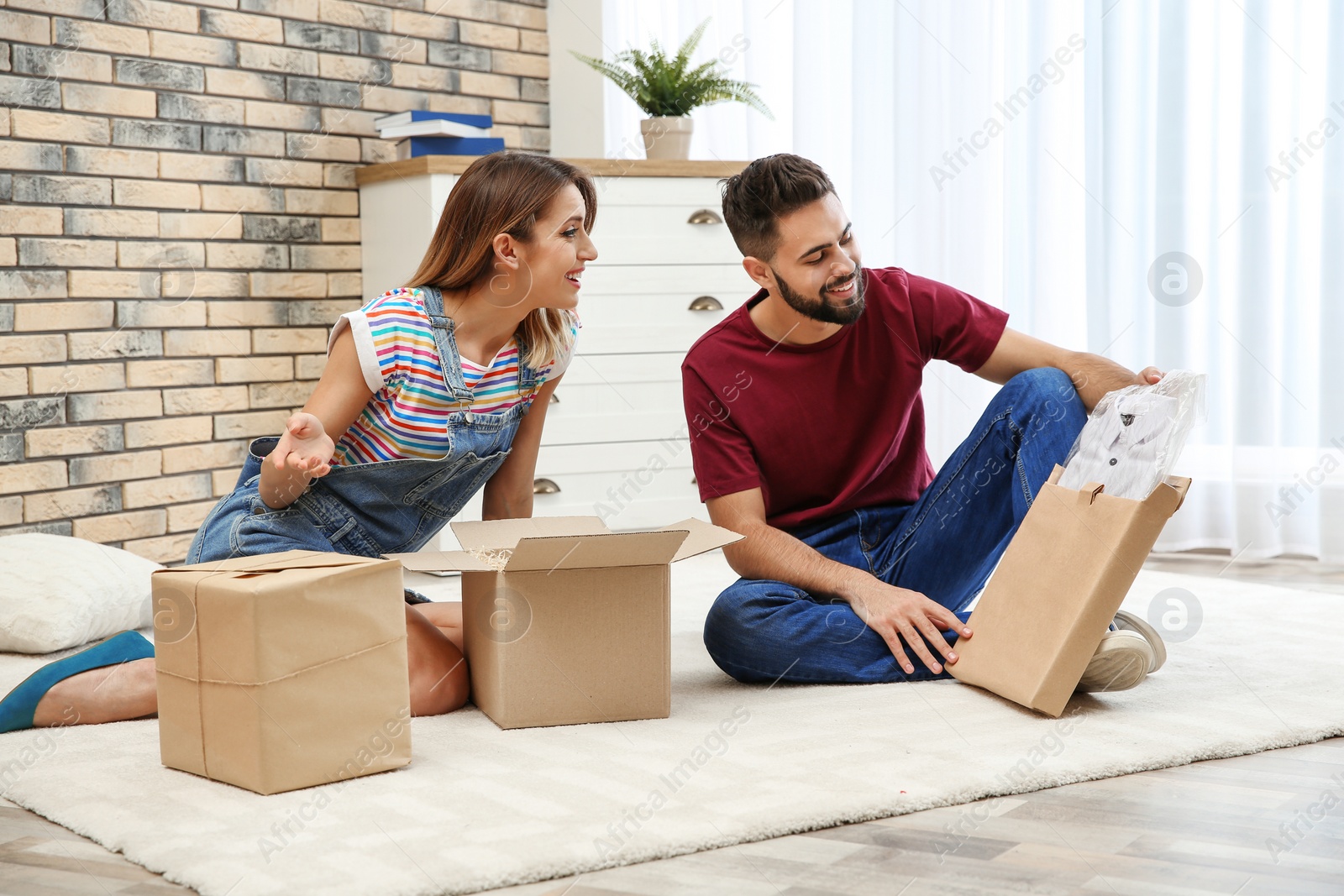 Photo of Young couple opening parcels on floor at home