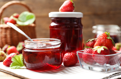 Photo of Delicious pickled strawberry jam and fresh berries on wooden table