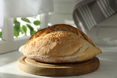 Photo of Freshly baked sourdough bread on white wooden table indoors