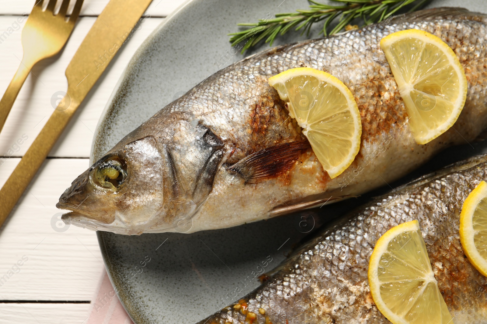 Photo of Delicious baked fish served on white wooden table, top view