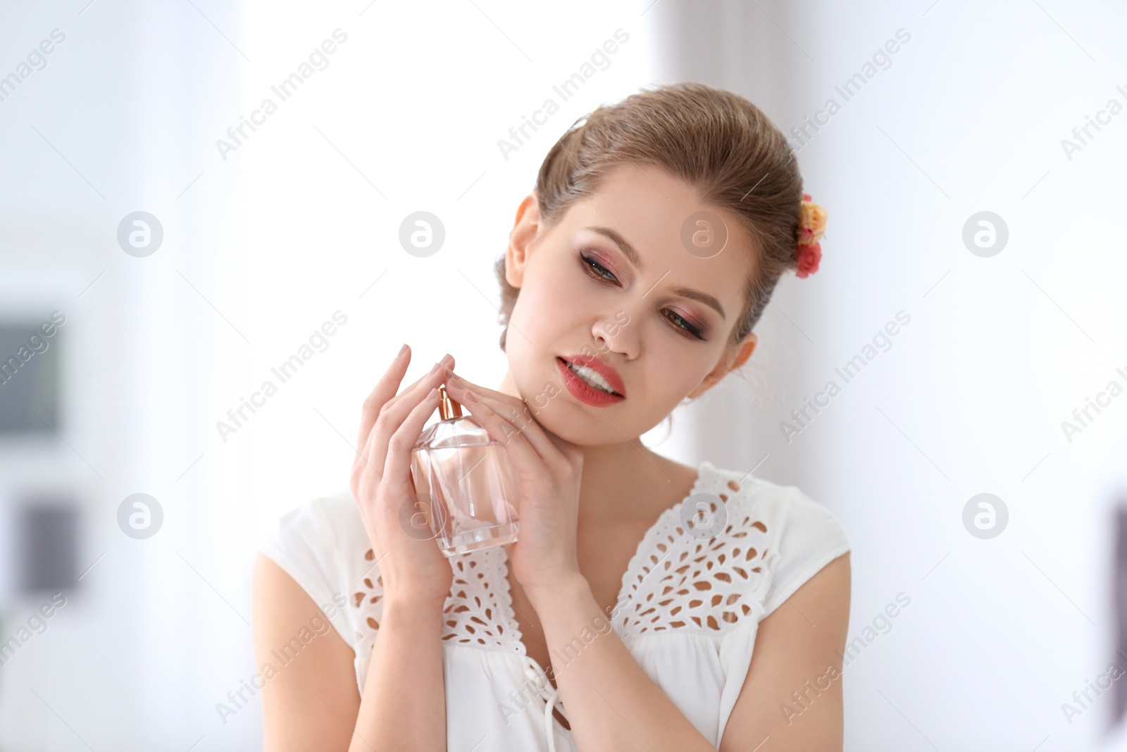 Photo of Beautiful young woman with bottle of perfume on blurred background