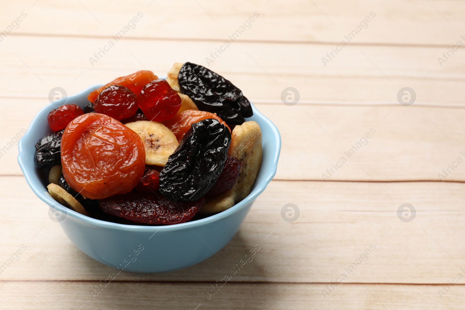 Photo of Mix of delicious dried fruits on white wooden table, closeup. Space for text