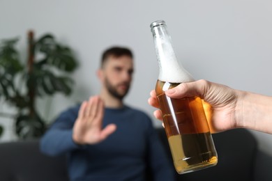 Man refusing to drink beer indoors, closeup. Alcohol addiction treatment