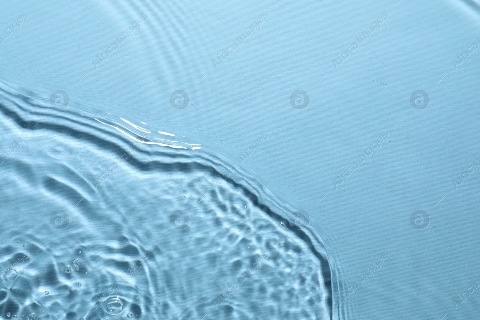 Photo of Rippled surface of clear water on light blue background, top view