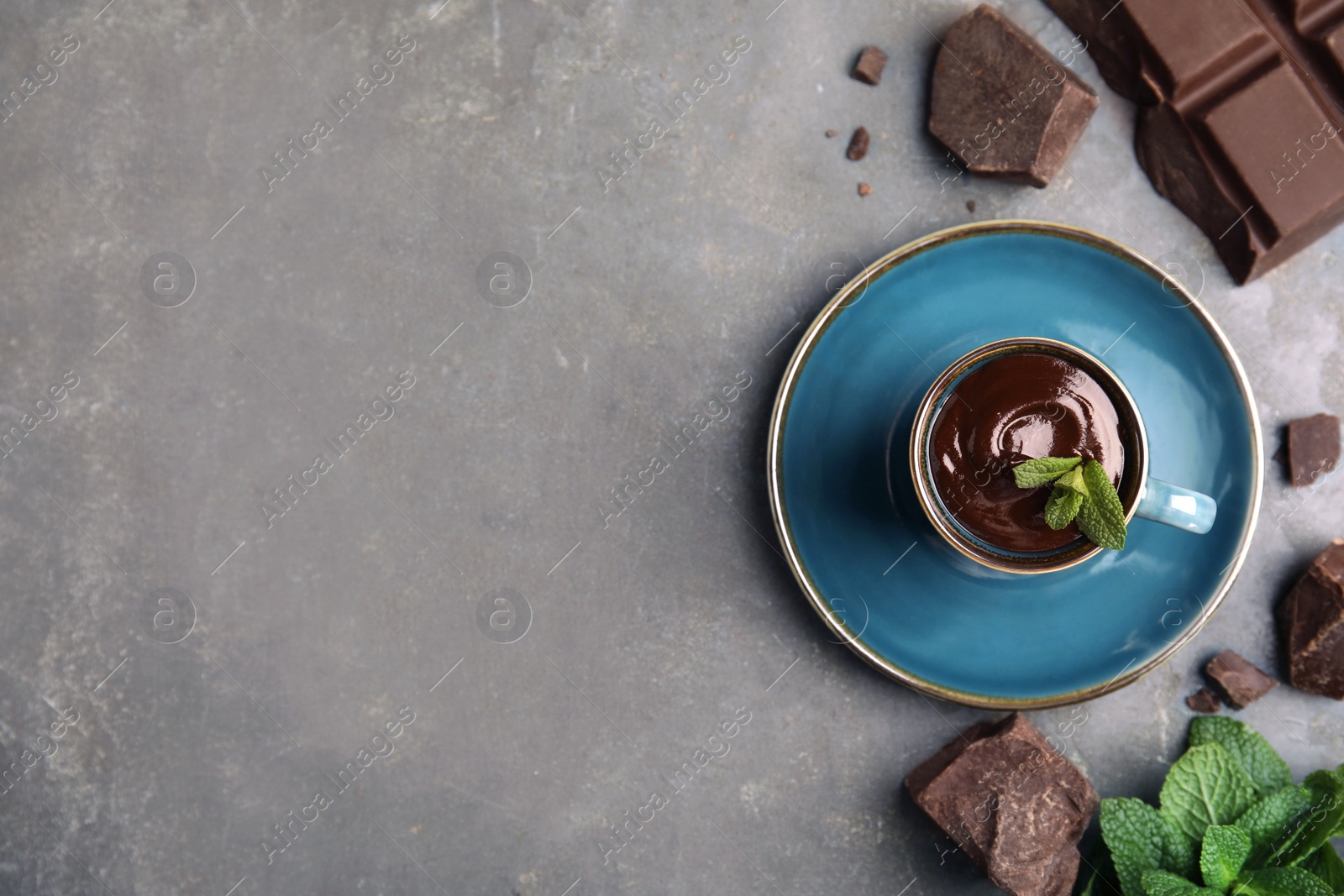 Photo of Cup of delicious hot chocolate, chunks and fresh mint on grey table, flat lay. Space for text