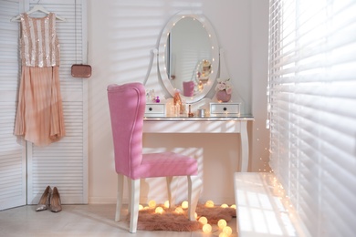 Photo of Elegant dressing table with lights and pink chair in stylish room interior