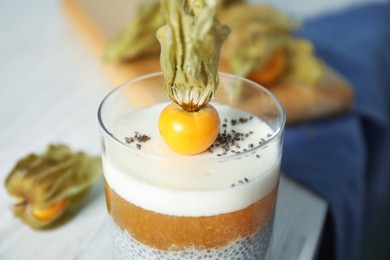 Photo of Delicious chia pudding decorated with physalis fruit on white table, closeup