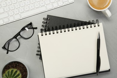 Flat lay composition with notebooks, glasses and coffee on light grey table