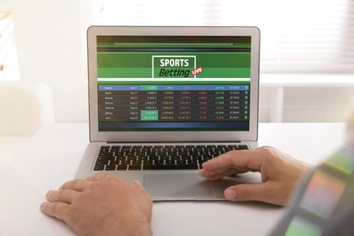 Image of Man betting on sports using laptop at table, closeup. Bookmaker website on screen