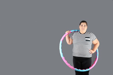Photo of Overweight woman with hula hoop and space for text on gray background