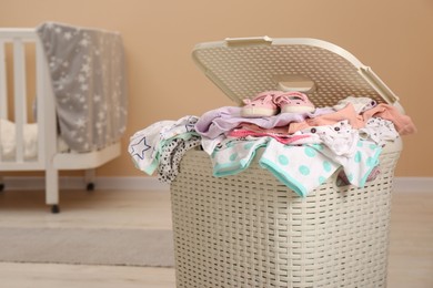 Photo of Laundry basket with baby clothes in child room, space for text