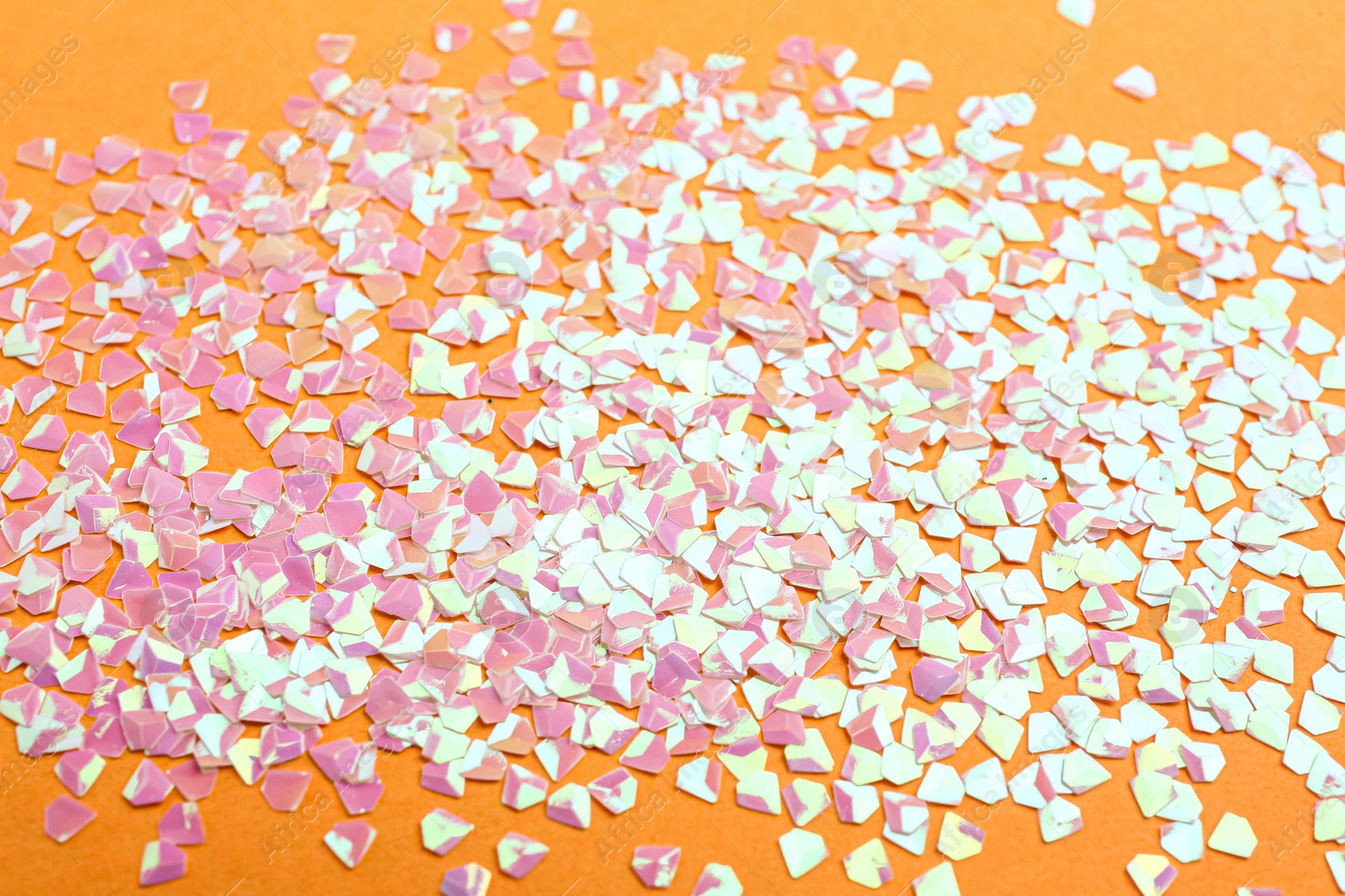 Photo of Shiny bright pink glitter on yellow background