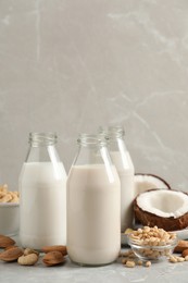 Photo of Different nut milks on light grey marble table. Space for text