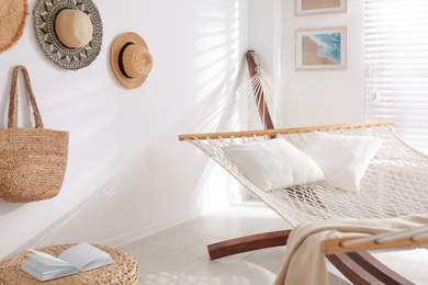 Photo of Comfortable hammock with pillows in stylish room. Interior design