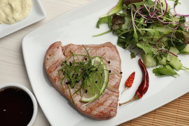 Photo of Delicious tuna steak served with salad and sauces on white wooden table, flat lay