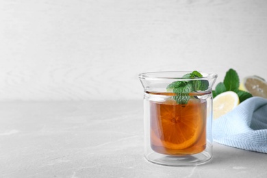 Hot tea with mint and lemon in glass on grey table. Space for text