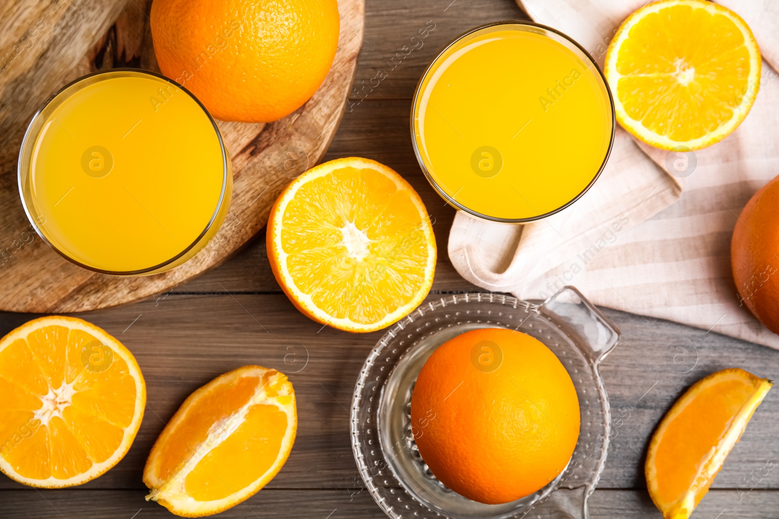 Photo of Fresh ripe oranges, squeezer and juice on wooden table, flat lay