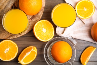 Fresh ripe oranges, squeezer and juice on wooden table, flat lay