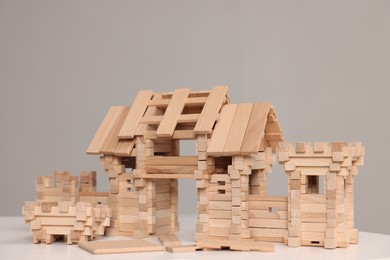 Photo of Wooden entry gate and building blocks on white table against grey background. Children's toy